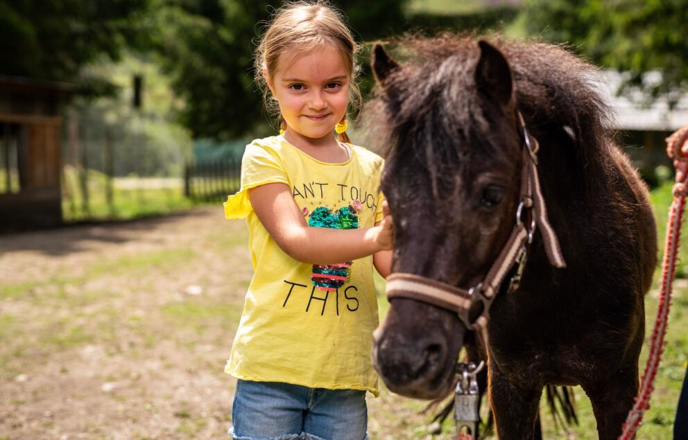 Mädchen steht zufrieden neben einem Pony.
