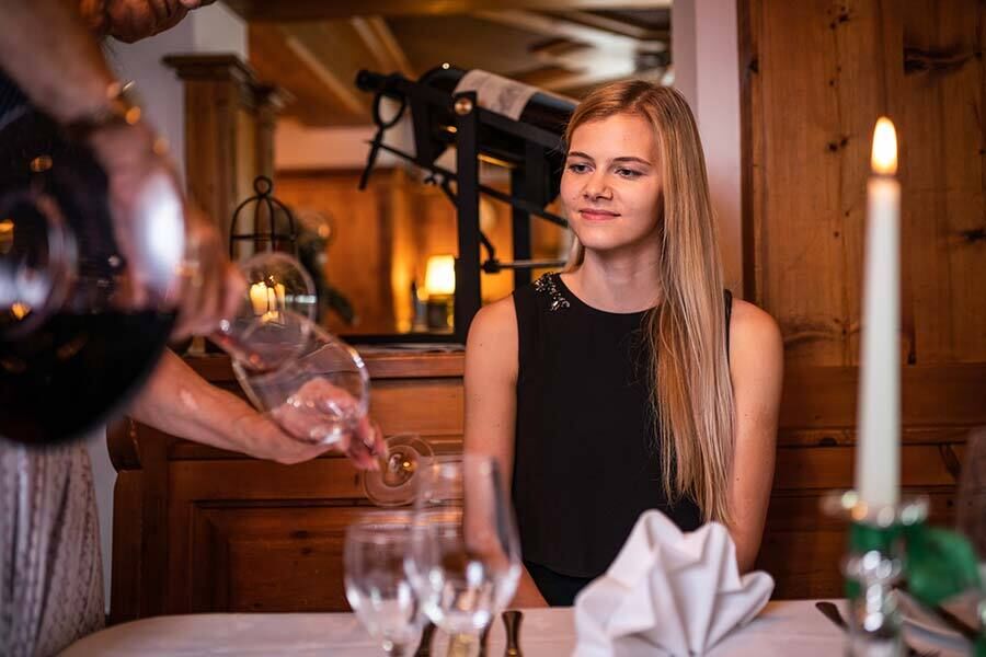 Una donna si siede al tavolo e si fa versare del vino all'Hotel GUT Trattlerhof in Carinzia.