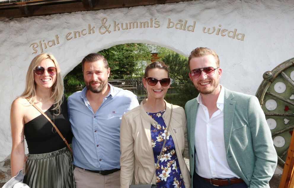 Two couples stand in the sunshine in front of the entrance to Trattlers Einkehr.