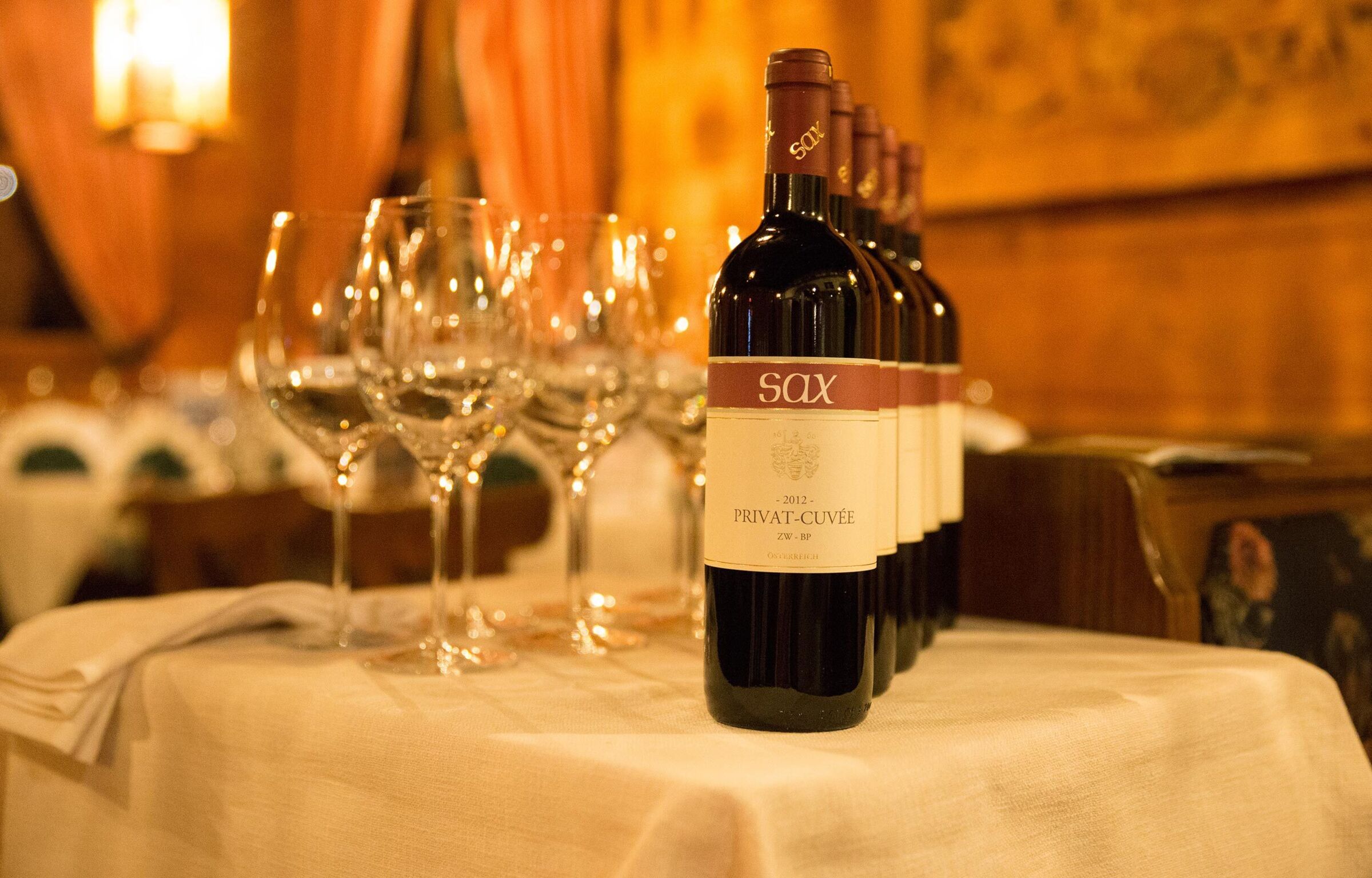 Wine bottle and wine glasses stand on a table with a white tablecloth