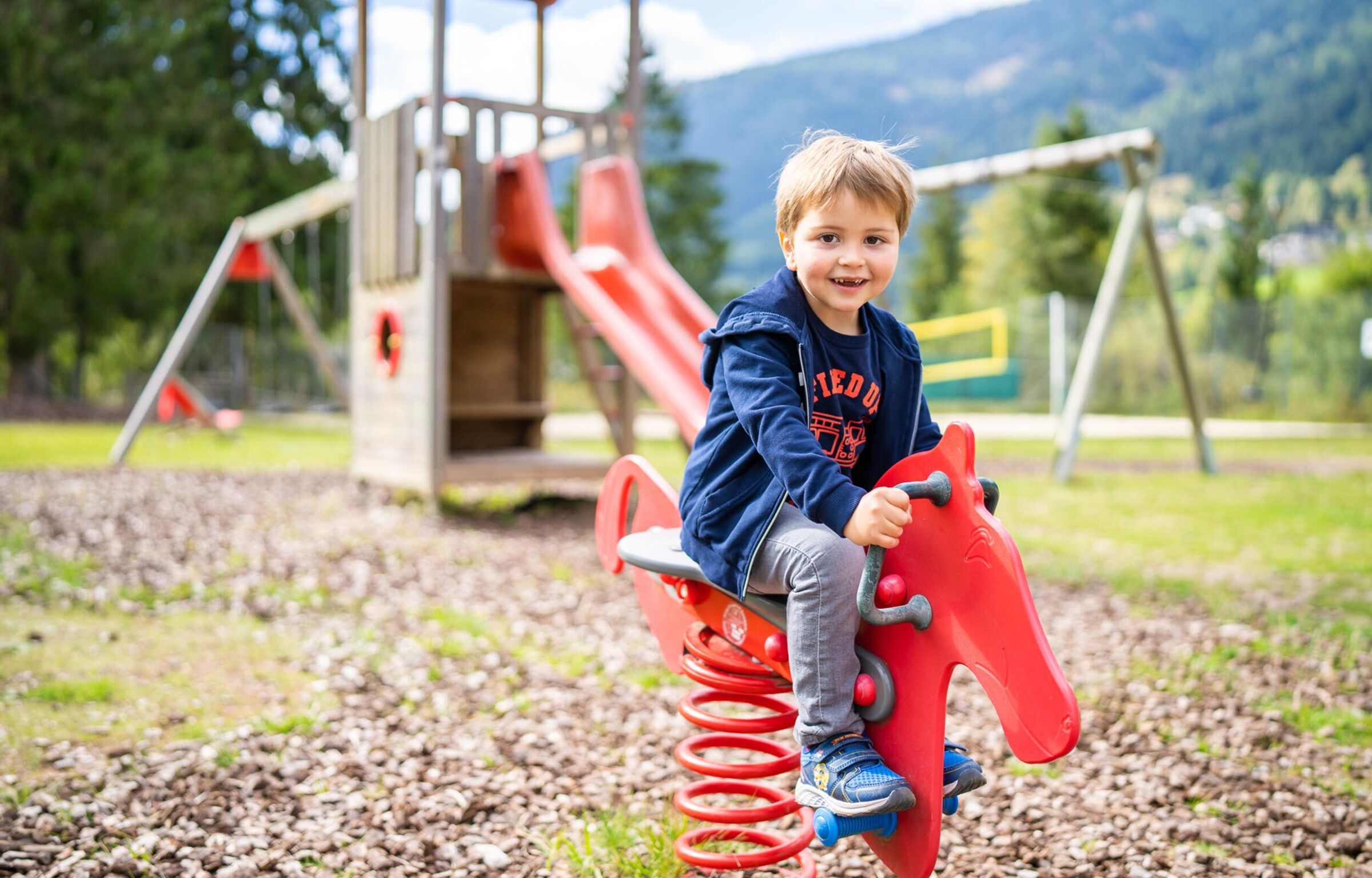 Un bambino al parco giochi siede su un'altalena a molla.