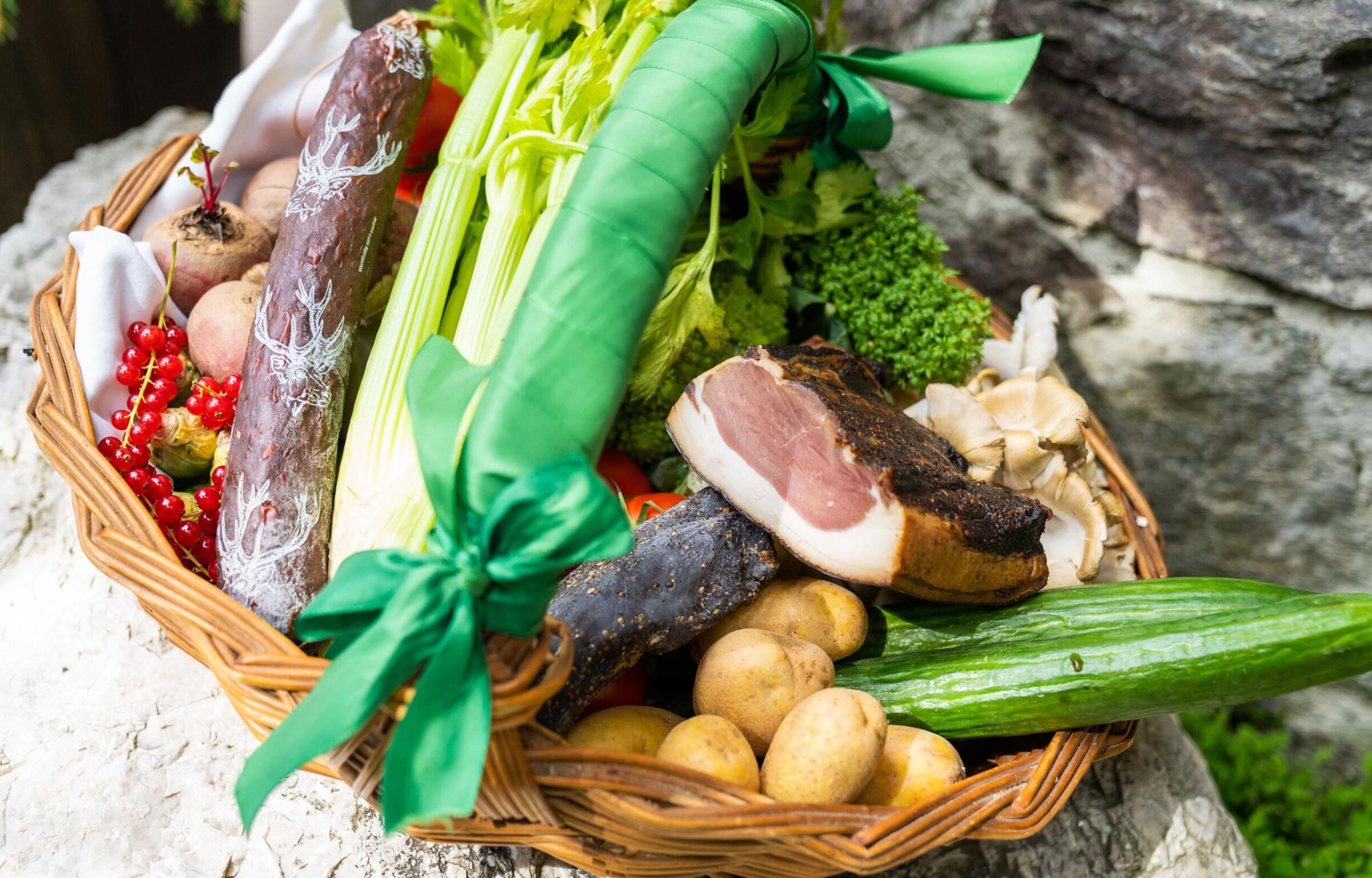 A basket full of regional products from bacon and salami to vegetables and potatoes.
