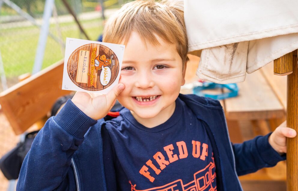 A little boy plays at the playground of Hotel Trattlerhof in Bad Kleinkirchheim and holds up a sticker