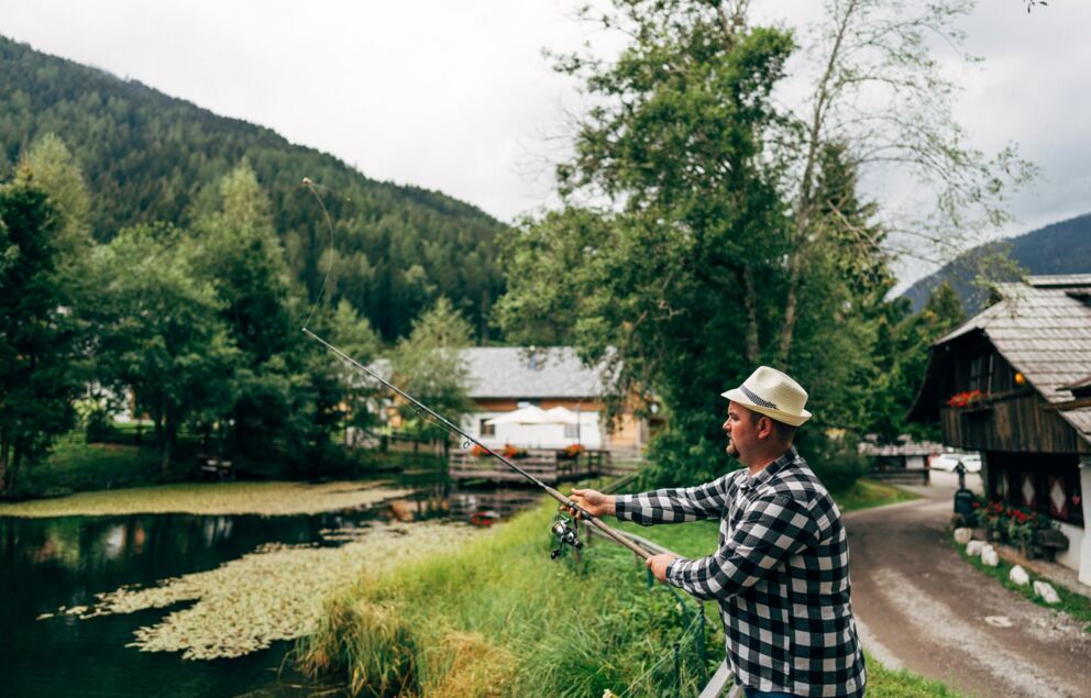 Man fishing in a pond in a small village.