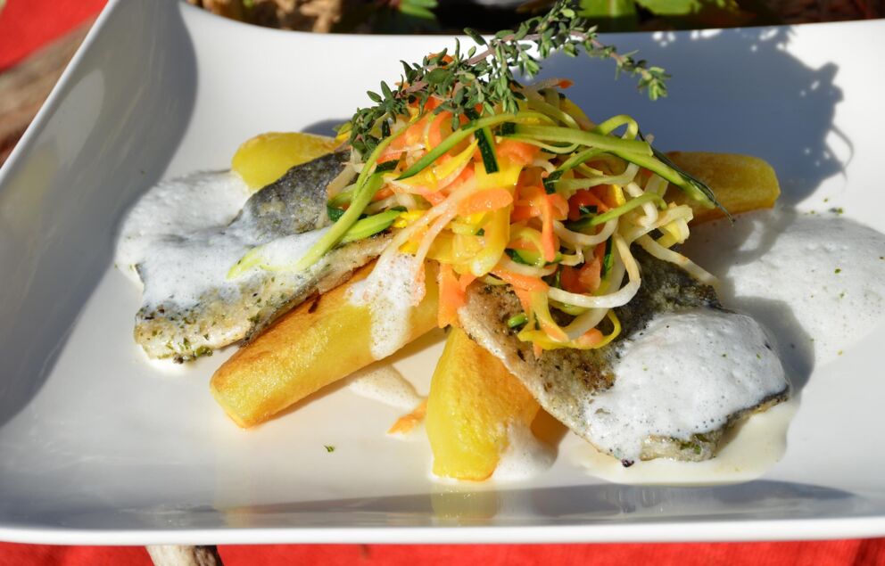 A fish dish with vegetables and potatoes on a white plate.