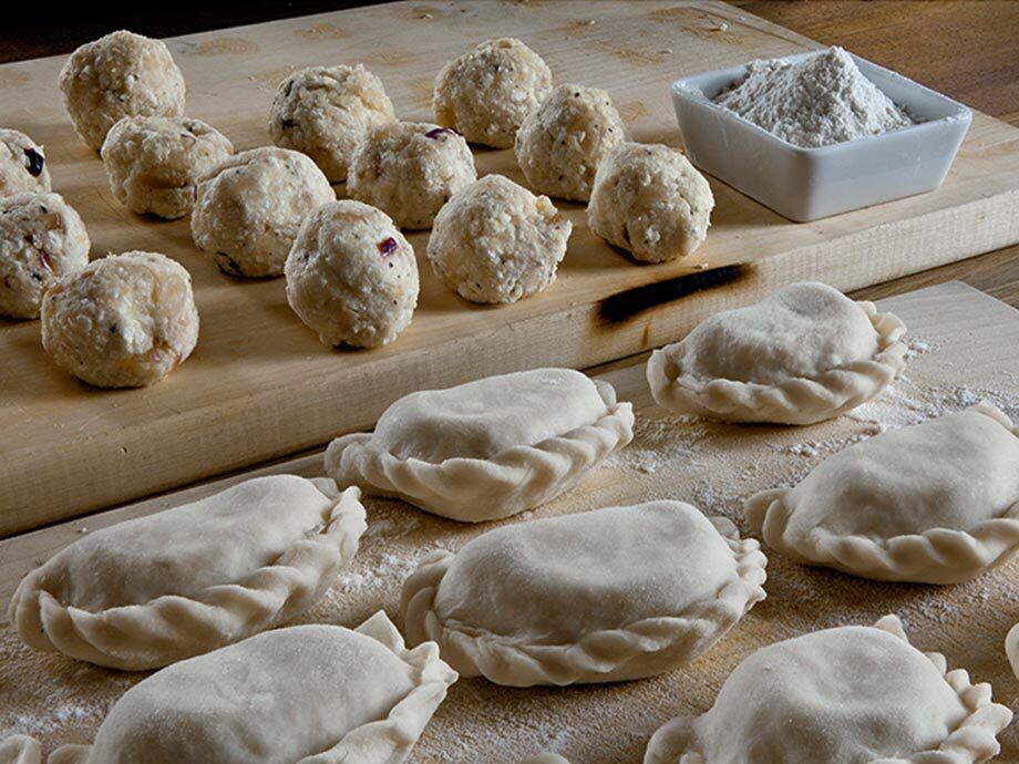 Filled dumplings lie on a wooden board.