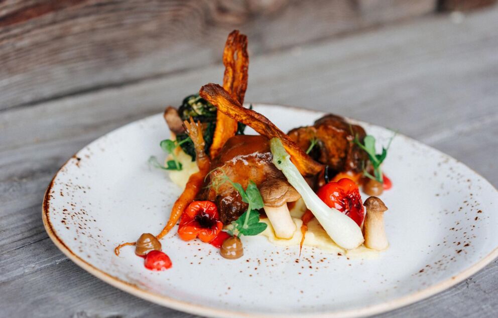 Meat dish with sweet potato fries, mushrooms and other vegetables lie on a plate.