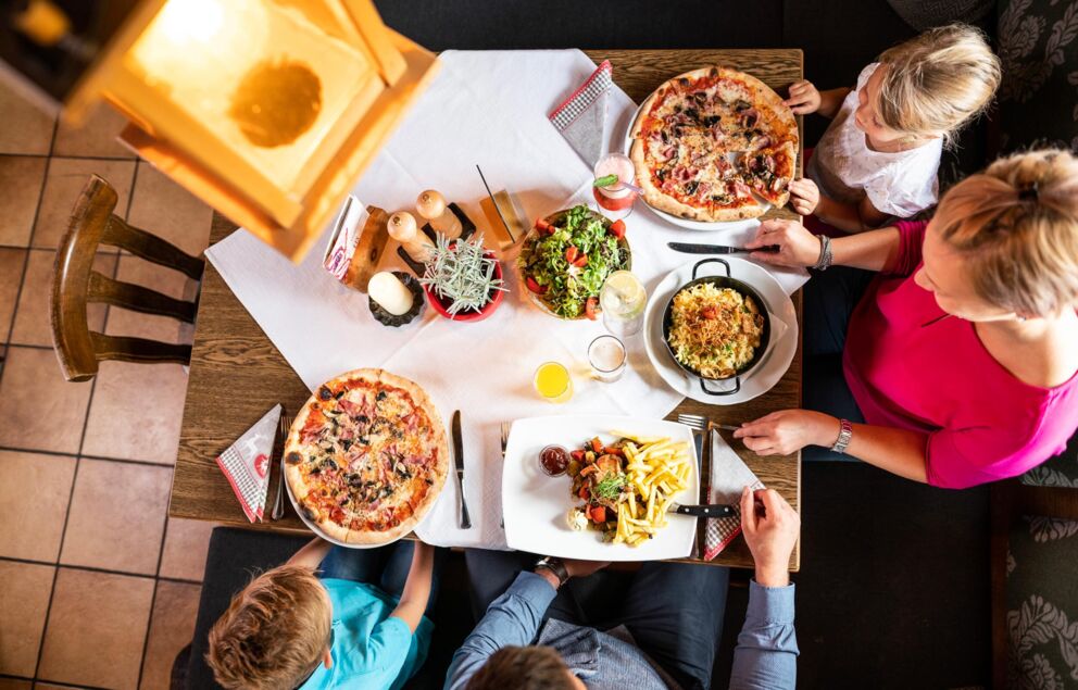 Family sitting in a restaurant eating and everyone eats something different.