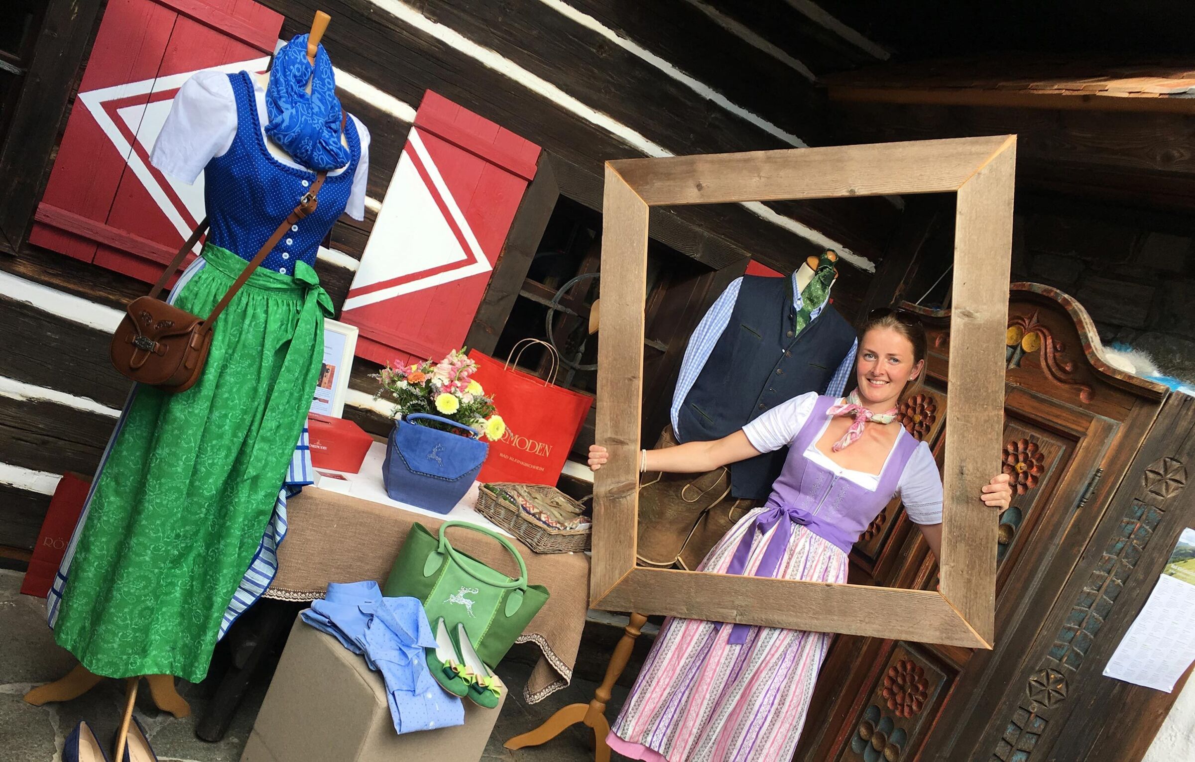 Woman with dirndl holds a large picture frame in her hand.