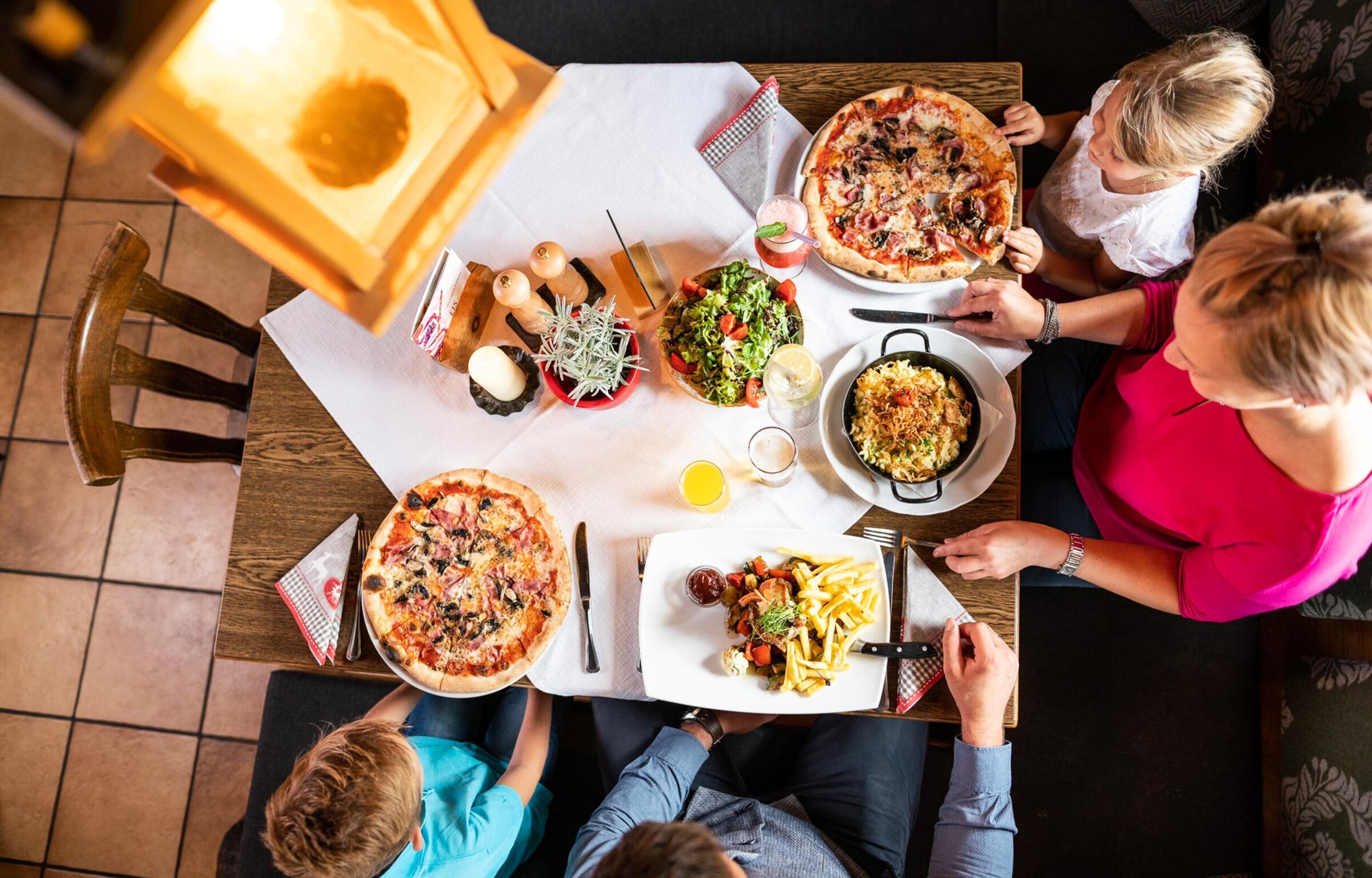 Familie sitzt in einem Restaurant beim Essen und jeder isst etwas anders.