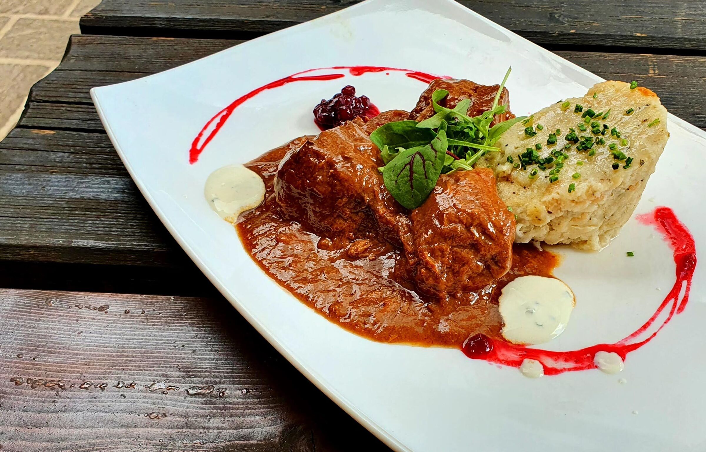 Bread dumplings with beef goulash on a white plate