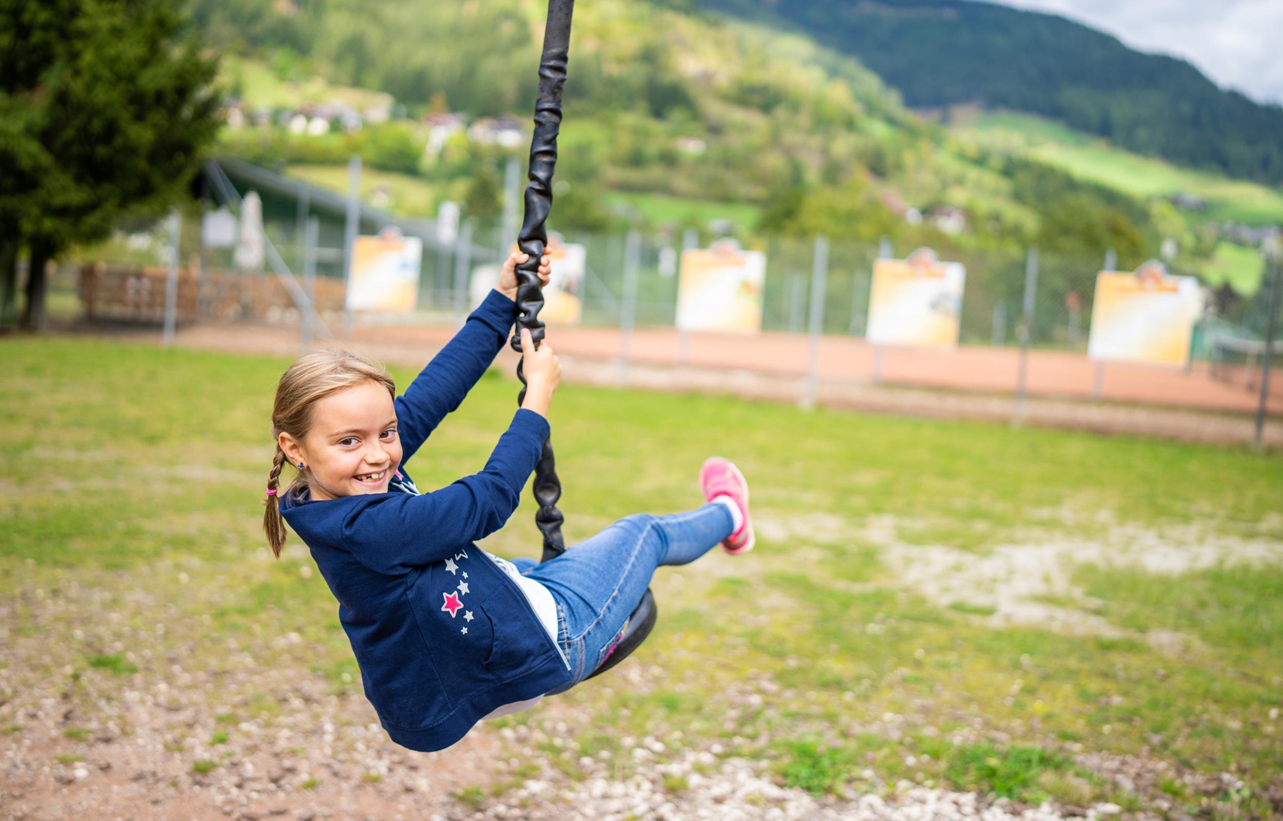 A girl in the playground is riding a zip wire.